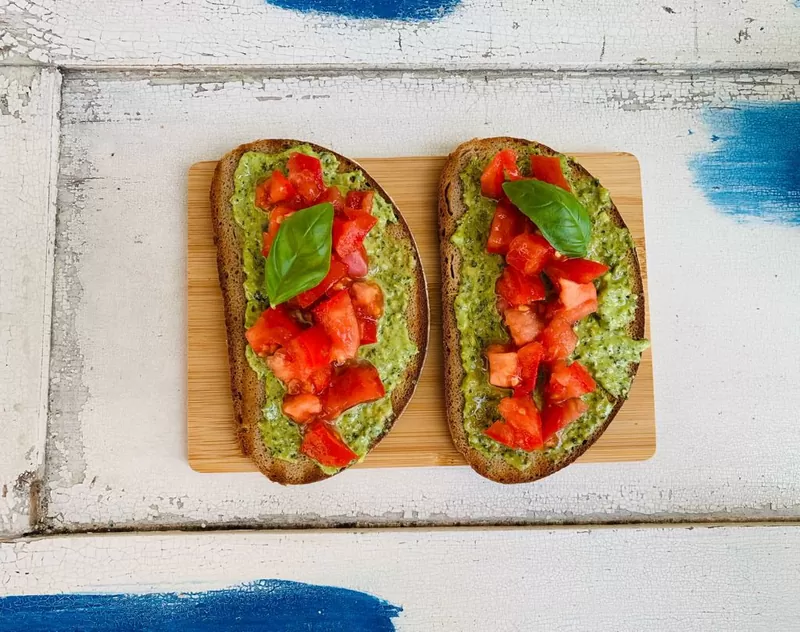 Bruschette con pesto e pomodoro su un tagliere di legno