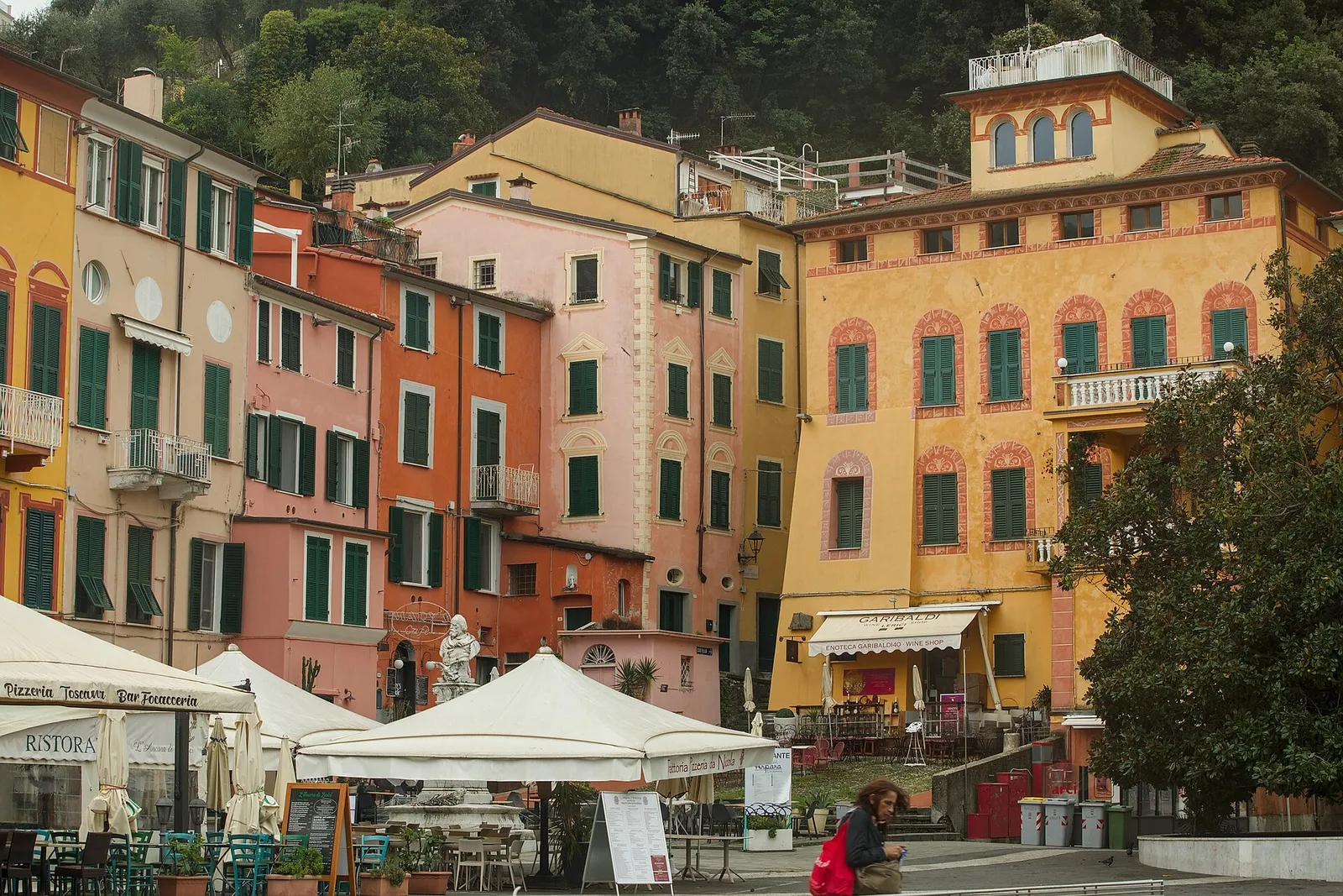 Piazza Garibaldi in Lerici: pastel buildings with green shutters, café umbrellas and the wooded hill behind