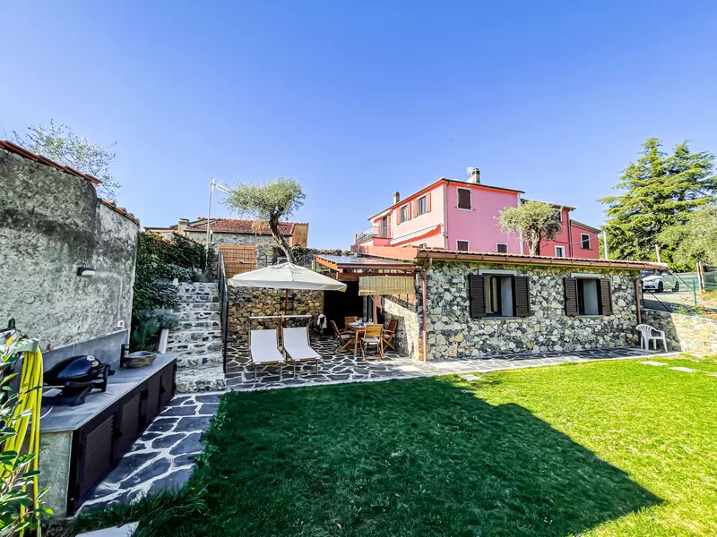 The private garden of I Particolari with its lawn, barbecue, parasol and stone house