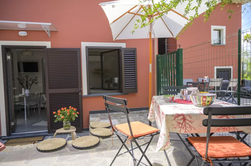 Il patio de I Pesci: facciata terracotta, ombrellone bianco e sedie a sdraio