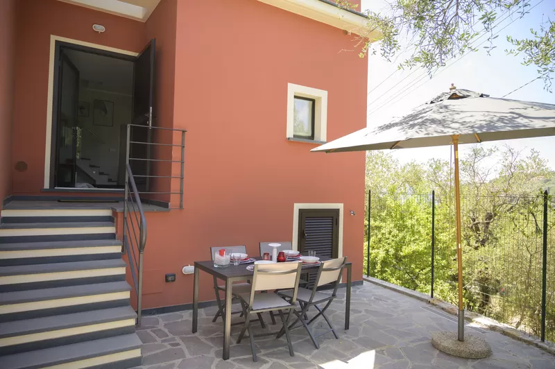 Il patio davanti alla facciata terracotta, con l'ombrellone
